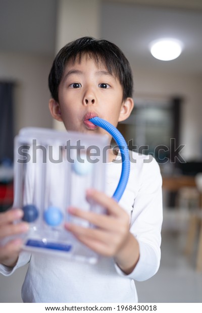 Thin boy uses a Tri-ball Incentive\
Spirometer for check his lung function at\
home.