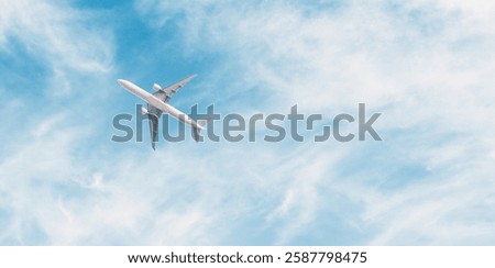 Thin clouds in the blue sky and bottom view of a flying passenger airplane.