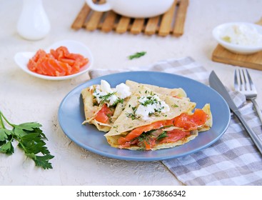 Thin crepe pancakes with salted salmon and cream cheese on a gray plate on a light concrete background. French cuisine. Pancake Day. - Shutterstock ID 1673866342
