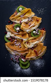 Thin Crepes With Cream, Kiwi, Pomegranate And Banana. Macro View. Pancakes Laid In The Shape Of A Christmas Tree