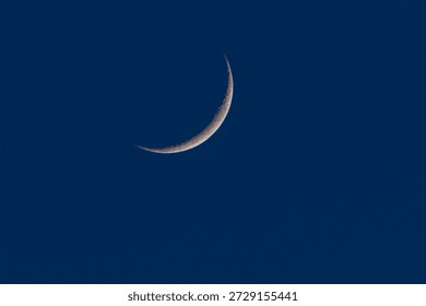 Thin crescent moon against a deep blue twilight sky. Minimalist night scene with copy space, calm atmosphere, astronomy and space concept, natural celestial background.