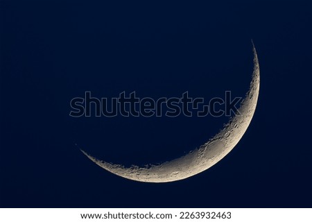 A thin crescent moon on a dark blue background
