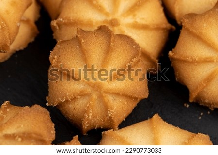 thin and crispy shortbread cookies on the table, crumbling shortbread cookies on a black slate board
