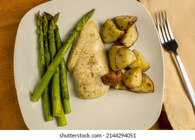 Thin Cut Chicken Breast Seasoned With Black Pepper Served With Asparagus And Red Potatoes