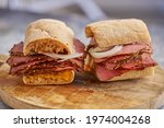 Thin cut pastrami sandwhich with delicious meet on baguette bread with chedder cheese, onion