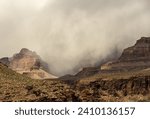 Thin Dark Clouds Break Over The Rim Of Grand Canyon on foggy day