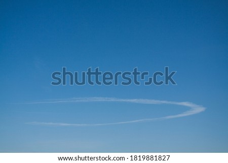 A thin ellipse-shaped cloud in the blue sky