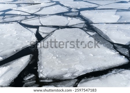 Thin ice over a river, with large shards of ice separated by gaps of ice-free water