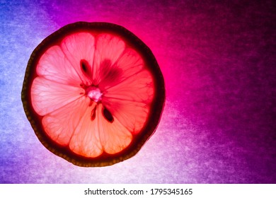 A thin lice of lemon macro capture, colorfully illuminated and back lit