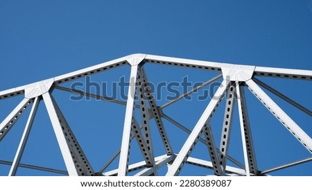 thin metal construction of bridge supports against blue sky colored background rivets and braces on metal beams background image