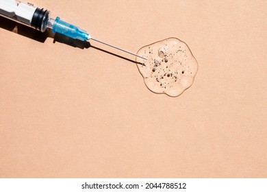 Thin needle in a transparent gel-like liquid with bubbles on a beige background. Top view, place for text.