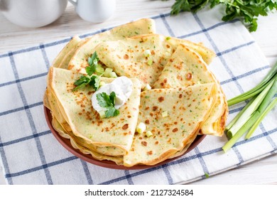Thin pancakes with herbs. Salty Pancakes with green onions. Wood background. Delicious food for a bite to eat. Traditional Russian pancakes for Maslenitsa.