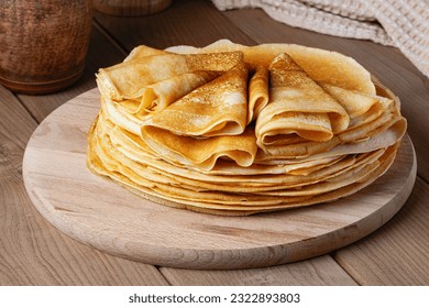 Thin pancakes on a wood plate. Homemade crepes, tasty food. Staple of yeast pancakes, traditional for Russian pancake week (Shrove tide). Thin pancake with crispy crust