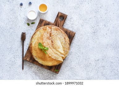 Thin Pancakes With Sour Cream And Honey On A Wooden Board On A Concrete Background. A Stack Of Pancakes. View From Above.