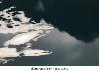 Thin sections of ice, creating a curious pattern on a navy blue mountain lake.