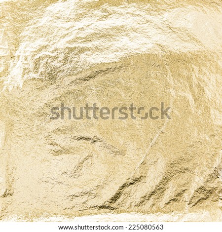 Thin sheet of golden leaf background with shiny uneven surface 