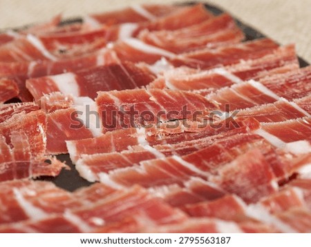 Thin slices of cured ham elegantly arranged on a serving tray, ideal for gourmet dining, catering events, Spanish cuisine and charcuterie concepts.