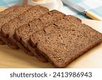 Thin slices of fresh baked brown linseed bread close up on a cutting board