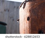 a thin spiderweb on the side of some rusted metal in light outside in the field in spring detail no spider