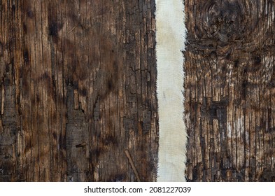 A Thin Strip Of Coarse Cloth On A Textured Wooden Surface. Ribbon With Uneven Jagged Edge On Dark Burnt Wood. Top View. Selective Focus.