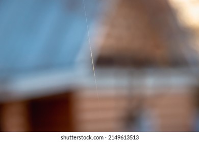 A thin thread of a cobweb against the background of a house in the village.