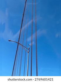 Thin vertical lines, likely cables from a bridge or transmission lines, set against a bright solid blue background. 
