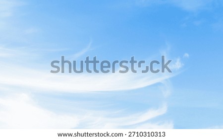 Thin white clouds blown by the wind in a beautiful blue sky on a windy summer day.