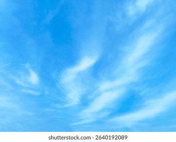 Thin White Clouds in a Bright Blue Sky. Minimalistic photo of thin white clouds scattered across a bright blue sky.