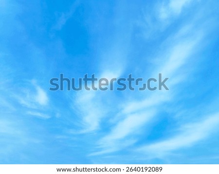 Thin White Clouds in a Bright Blue Sky. Minimalistic photo of thin white clouds scattered across a bright blue sky.