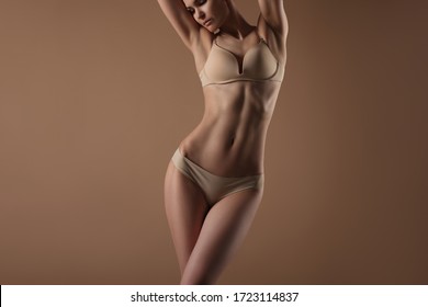 Thin young woman in underwear on beige background. Fitness, diet, skin and body care