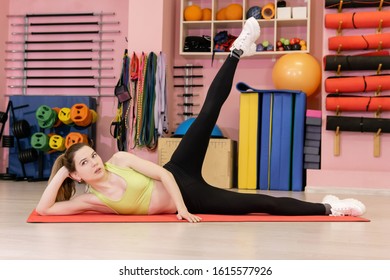 Thin Young Woman Who Has Recently Started Exercising Is Engaged In The Gym, Does A Side Lying Leg Lift