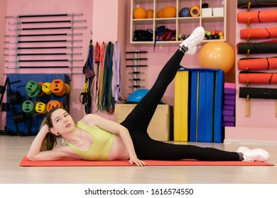 Thin Young Woman Who Has Recently Started Exercising Is Engaged In The Gym, Does A Side Lying Leg Lift