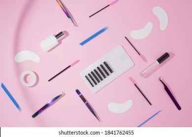 Things for the work of lash-makers, artificial eyelashes, microbrachis, glue, tweezers, combs, brushes for eyelash extensions. Eyelash extension, painting of eyebrows. Top view, pink background.
