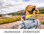 Thingvellir, Iceland - August 12, 2024: A woman taking photos of views of Strokkur Geyser in Iceland
