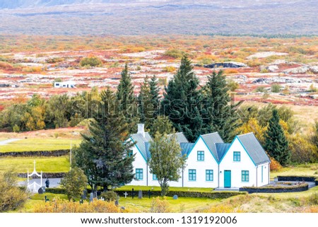 Thingvellir National Park with colorful yellow orange autumn foliage during day in Iceland Golden circle and farmhouse with people tourists cemetery