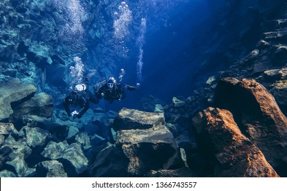 Thingvellir, Silfra / Iceland - April 5th 2019: Snorkelers And Scuba Divers Swimming In Famous Popular Fissure Drift With Blue Crystal Clear Glacial Water Between Tectonic Plates Mid Atlantic Ridge