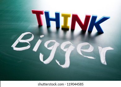 Think bigger concept, words on blackboard