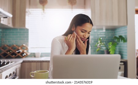 I think I bit my gum thats so painful. Shot of a young businesswoman suffering from a tooth ache while eating an apple at home. - Shutterstock ID 2143576319
