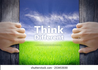 "Think Difference" Motivational quotes. Hands opening a wooden door then found a texts floating among new world as green grass field, Blue sky and the Sunrise.