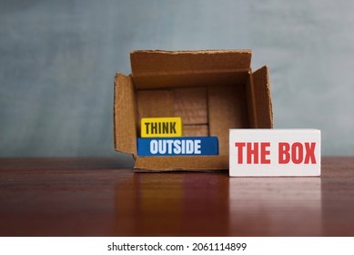 Think Differently, Unconventionally, Or A New Perspective Concept. Box And Wooden Cube With Text THINK OUTSIDE THE BOX