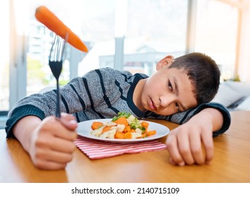 I Think Ive Lost My Appetite Now. Shot Of An Unhappy Young Boy Refusing To Eat His Vegetables At Home.