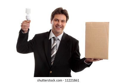 Think Outside The Box.  A Businessman Balancing A Box & Holding Energy Efficient Light Bulb.   Eg  Ideas, Lateral Thinking, Unconventional,  Sustainable Energy, Innovation, Environment  Issues