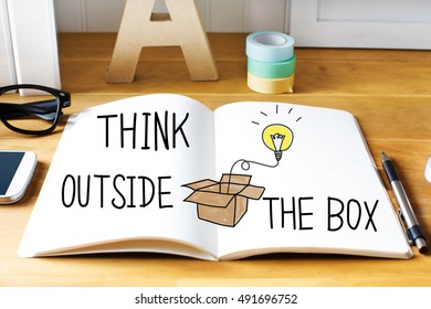 Think Outside The Box concept with notebook on wooden desk 
