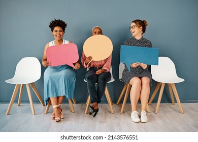 I think I shouldnt have said that. Studio shot of a group of attractive young businesswomen holding speech bubbles while sitting in a row against a grey background.