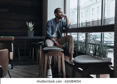 Thinking about... Thoughtful young man holding hand on chin and looking outside while sitting in the cafeteria - Shutterstock ID 626384054