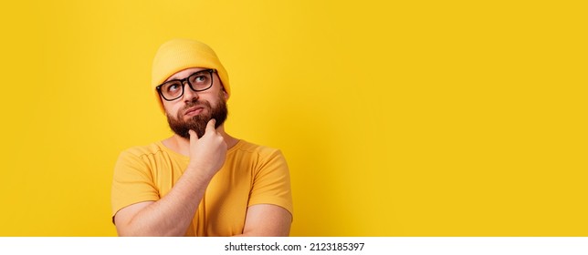 thinking bearded man looking up over yellow background, panoramic layout