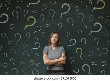 Thinking Business Woman In Front Of Question Marks Drawn On Blackboard