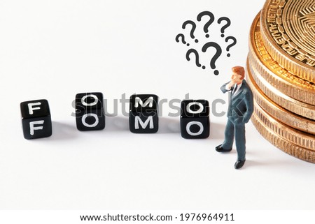 Thinking businessman figurine looking at cubes next to bitcoin stack. Scattered black cubes with FOMO text on white background.  Cryptocurrency, blockchain or trading concept.