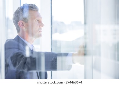 Thinking businessman in the office looking through the window - Powered by Shutterstock