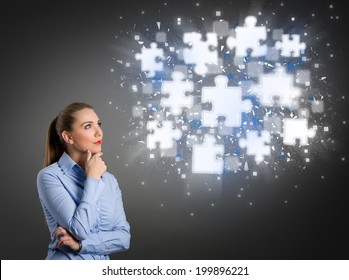 Thinking businesswoman looking at clouds of shining puzzle pieces - Shutterstock ID 199896221